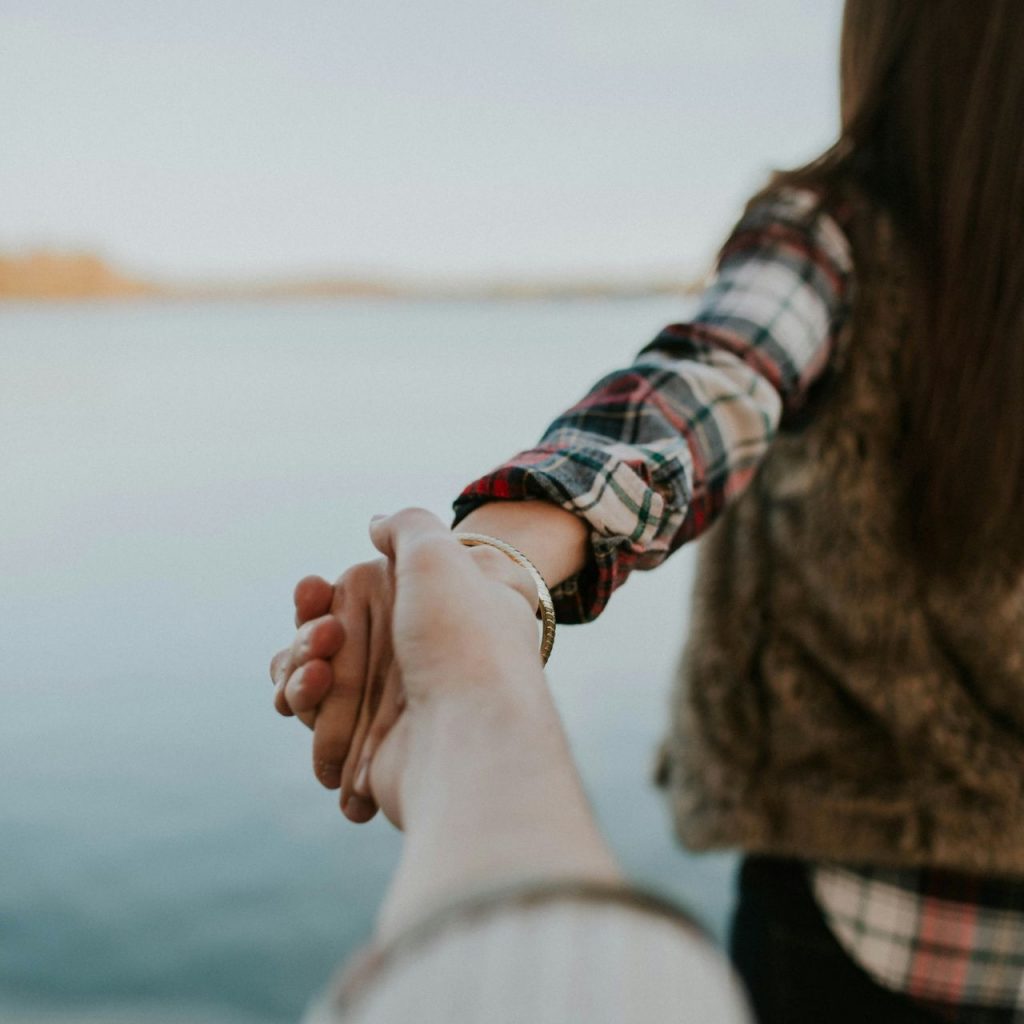 Foto von Brooke Cagle auf Unsplash Fotografie von Mann und vorausgehender Frau, die Händchen halten.