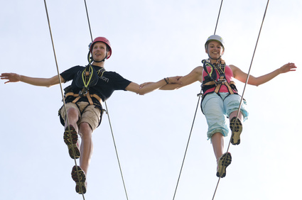 Händchenhaltendes Paar auf einem Drahtseil gehend.